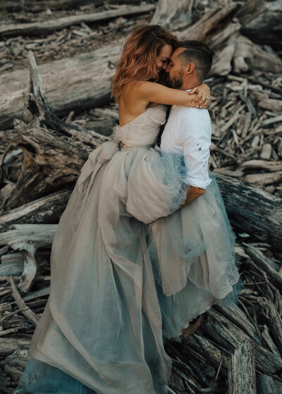 Couple embraces in a hug in a photograph at an Oregon elopement in a sweet caroline untraditional wedding dress