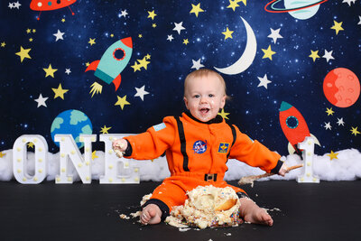 boy in astronaut costume smiles with his smash cake