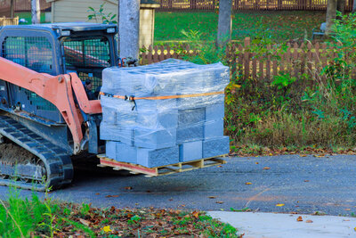 as-worker-unloads-a-small-tractor-he-lifts-pallets-2023-11-27-05-30-32-utc