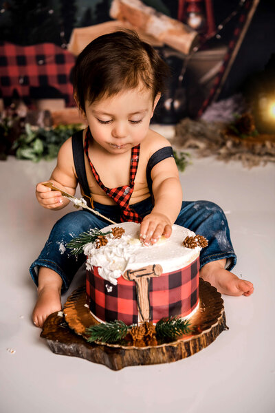 Portrait Photographers CT document sweet moment as baby enjoys buffalo plaid decorated cake during lumberjack themed cake smash