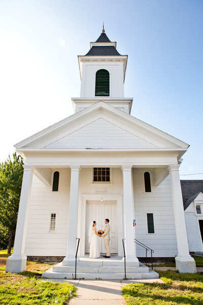 a bride and groom in front of a historic curch