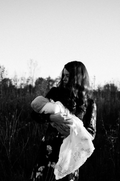 Woman holding her newborn baby during photography session with Laurie Baker