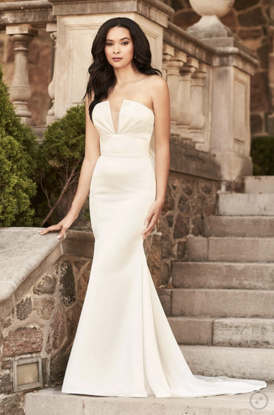 Paloma Blanca Style 4884 is a luxurious satin gown with tasteful cut outs on the bodice, and a removable bow and train on the back. Perfect if you are looking for two different looks on your wedding day! The empire and waist seam details on the bodice will provide excellent definition at your waist, perfect for Banana body types.