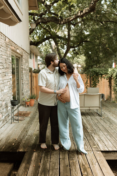 Pregnant woman posing with husband in their backyard