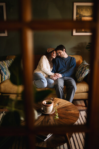 Couple snuggles close on their living room couch 