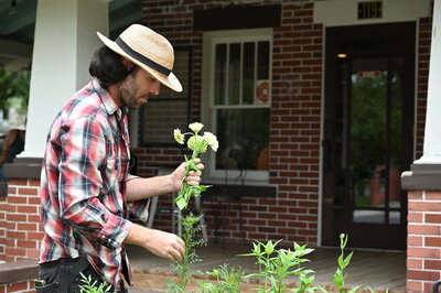 Farmer Will outside of Hillcrest Coffee picking flowers in the garden