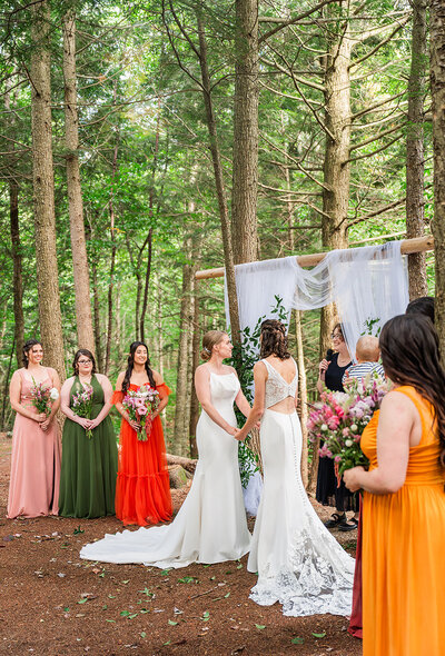 two brides at the alter with their bridesmaids