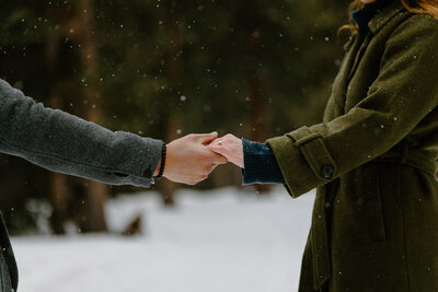 An engaged couple holds hands while taking Engagement Photos in front of the Flatirons in Boulder, Colorado.