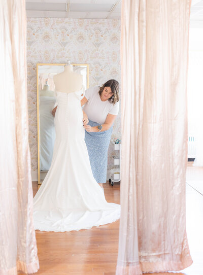 Kirstyn, the owner of Bridal Alterations by Kirstyn on Long Island, sitting on a green sofa in a well-decorated room