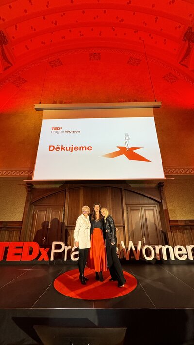 tři ženy stojí na typickém červeném kulatém koberci na TED konferenci TEDxPragueWomen