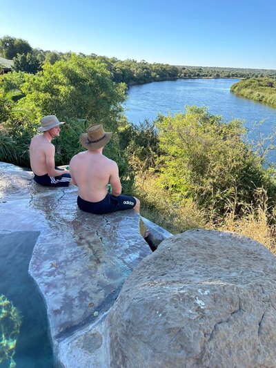 People in infinity pool, looking out on the Okavango river