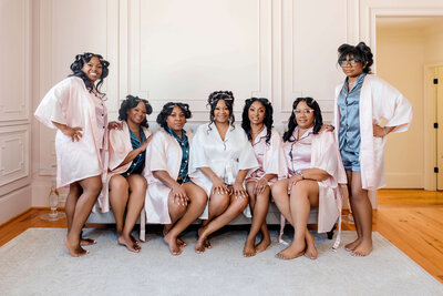 Bride and bridesmaids sharing a joyful moment in matching robes before the wedding day festivities.