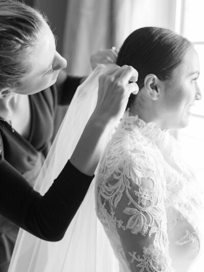 black and white image of wedding planner placing bride's veil