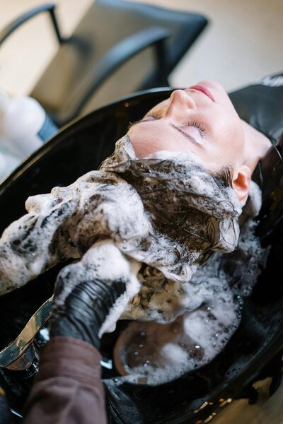 Client having hair washed in the shampoo bowl