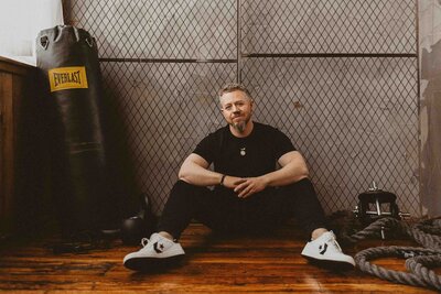 man sitting on the floor with gym accessories at the side