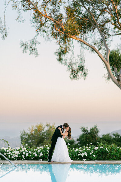 groom dipping his bride at the end of the pool at the Belmond El Encanto wedding in Santa Barbara, CA