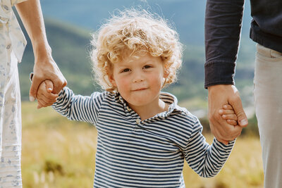 Close of image of child holding his parents hands evoking emotion and curiousity