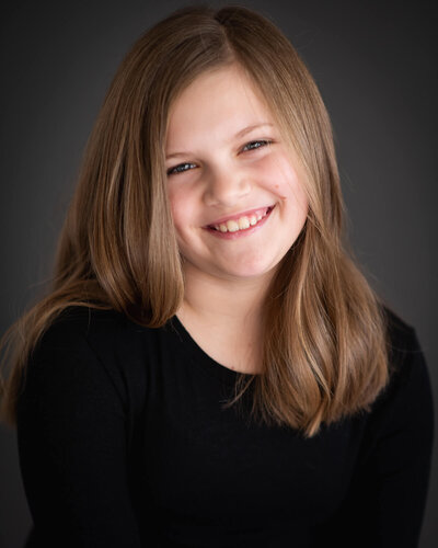 ten your olf girl with sweet smile in black shirt on a dark background