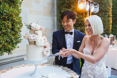 Wedding couple getting married at the Greystone Mansion in Southern California. BThe couple is cutting the wedding cake.