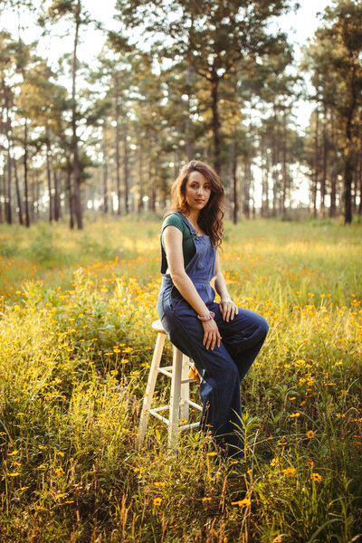 woman standing in field of wild flowers with trees in the background