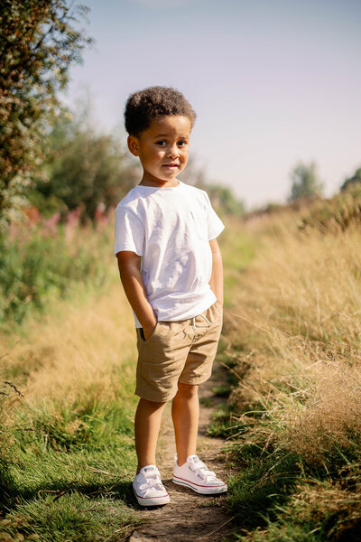 A full length portrait of a boy during a summer family shoot