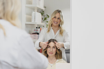 Geelong Hairdresser Grace Cleave  brushing a clients hair in the mirror