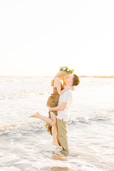 A woman leaps into a man's arms and gives him a kiss at Galveston Beach at sunset
