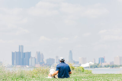Dogology University trainer sitting with a white dog, both looking at the horizon after a training session