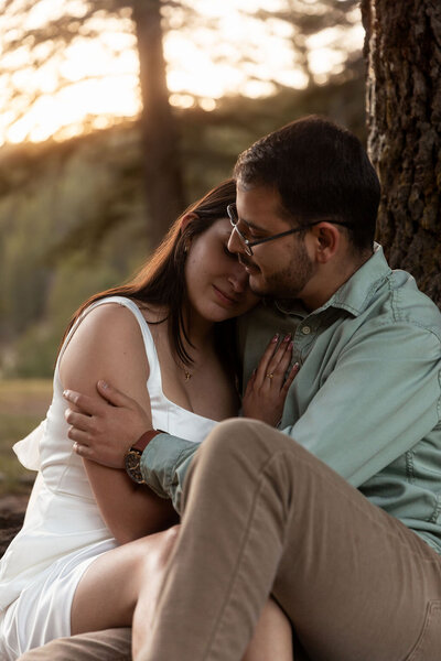 Couple hugging and sitting while leaning against a tree during a Utah session, captured by Lamblight Photography