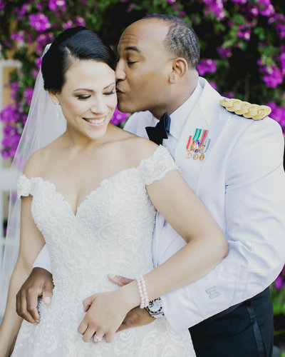 Groom standing behind Bride kissing her temple as she smiles