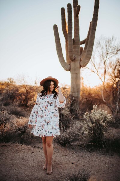 woman smiling touching hat in desert