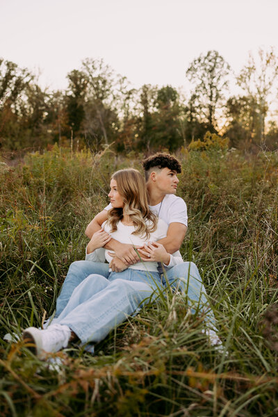 Couple sitting in the grass taking engagement photos in the midwest
