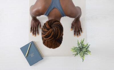 african american wpman planking with  blue fitness journal lying on her right side