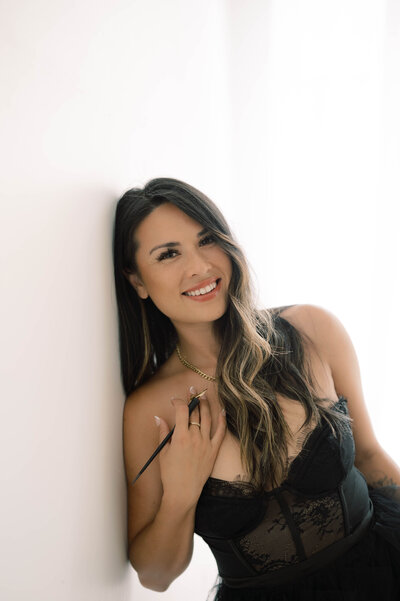 Cat Lauren Calligraphy leaning against a wall in a black lace dress