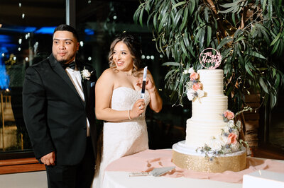 Bride and groom smiling at their loved ones during their cake cutting - by wedding photographer Daniella Diaz Photo