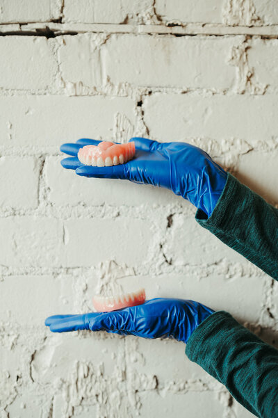 A set of dentures made by Kalispell Denture Clinic rests atop a wood decor table.