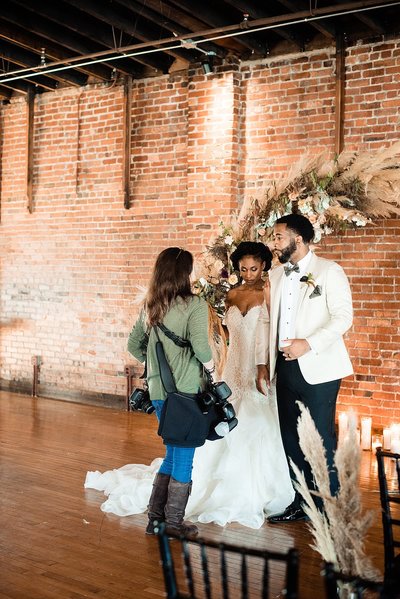 Wedding photographer chatting with bride and groom in front of round arbor at Cannery ONE