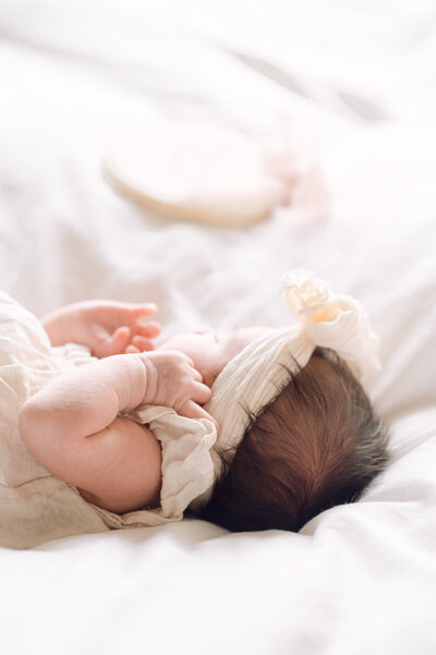 Softly lit photograph of a newborn baby wearing a bow headband, captured by a Northern Virginia family photographer during a lifestyle session.