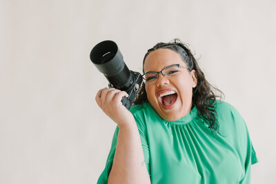 A photographer holding up a camera and smiling big