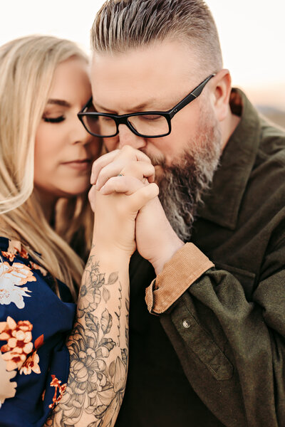 Family Photographer,  couple with eyes closed holding hands while husband kisses them