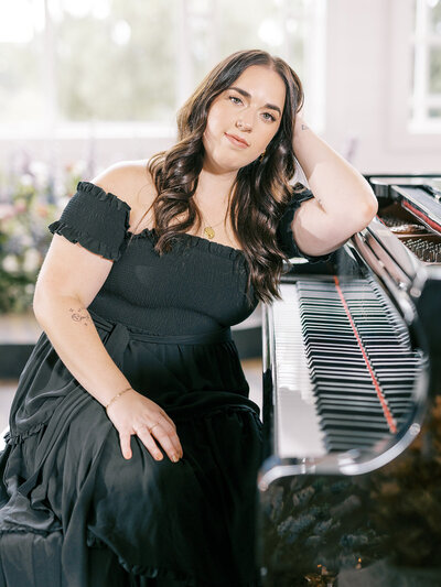 Mikaela Kahn live wedding singer leaning on a piano
