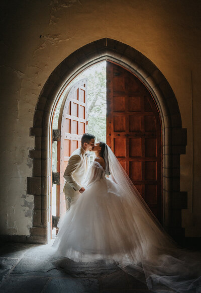 Wedding couple kissing in front of an arched door