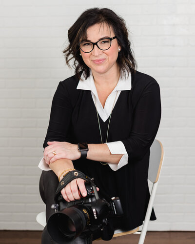photographer Elenora Luberto of JEMMAN Photography sitting in a chair holding a camera