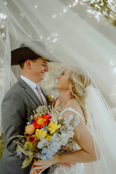 bride and groom going in for a kiss underneath brides veil