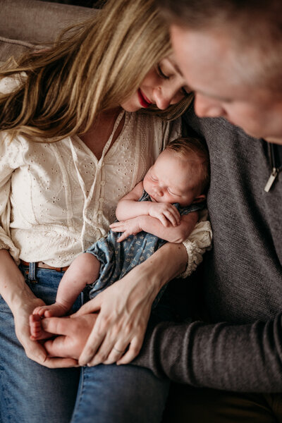 Baby in moms arms with dad looking at them