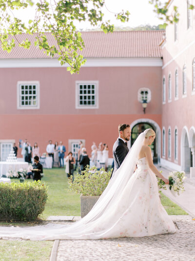 bride in Monique lhuillier gown and groom walk into cocktail hour at the Ritz in Sintra Portugal