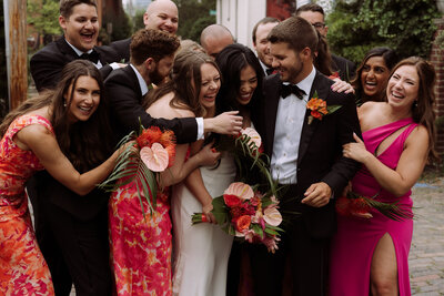 wedding party hugging bride and groom, candid wedding photograph