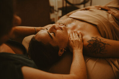 A licensed esthetician gently cradles the face of a client while performing relaxing face massage.