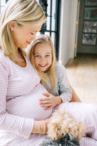 A mother and daughter sit closely together during an in-home maternity session.