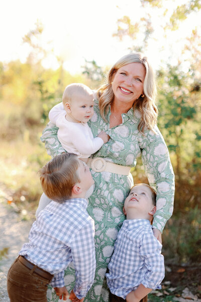 mom smiling at the camera while holding and snuggling her sons